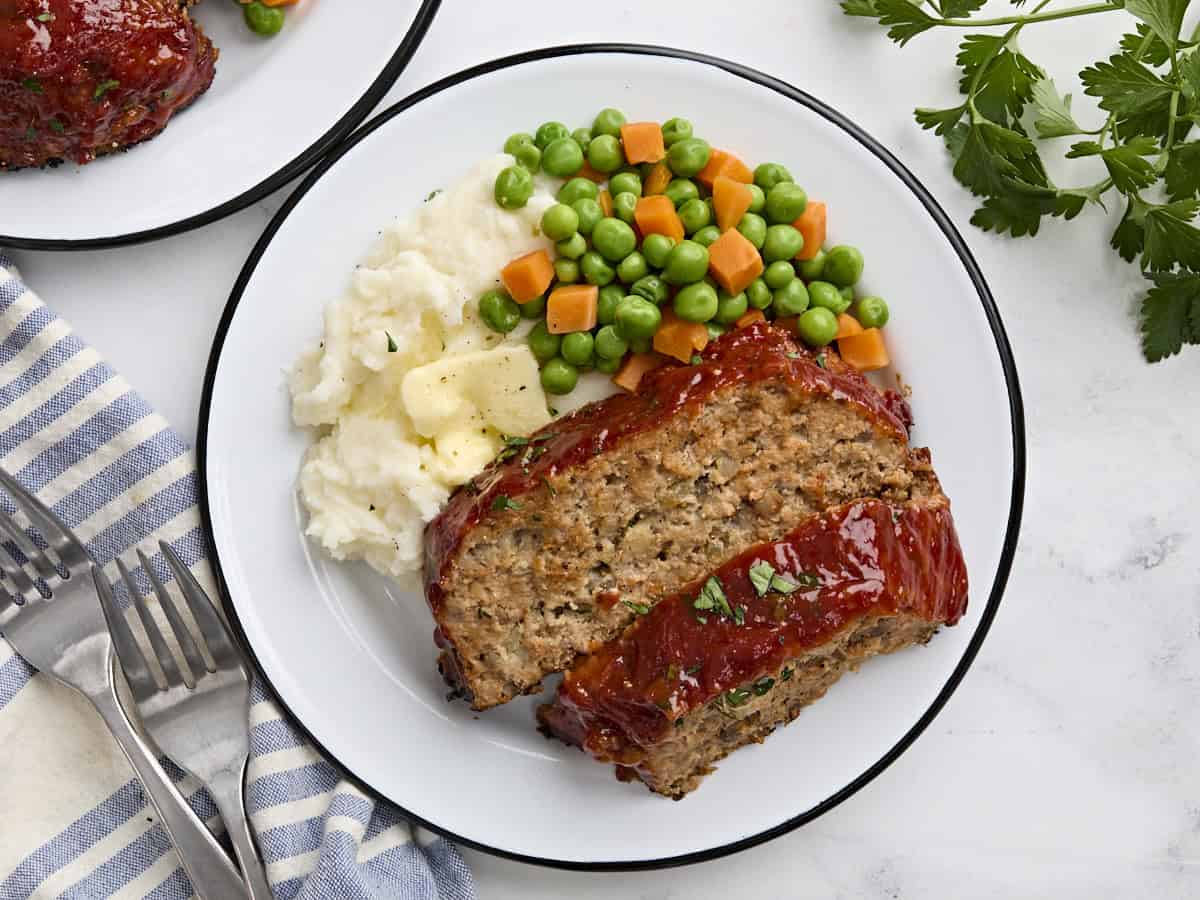 Overhead view of two turkey mushroom slices on a plate with mixed vegetables and mashed potatoes.