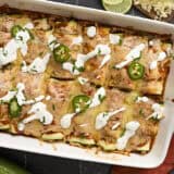 Overhead view of zucchini enchiladas topped with sour cream and sliced jalapenos.