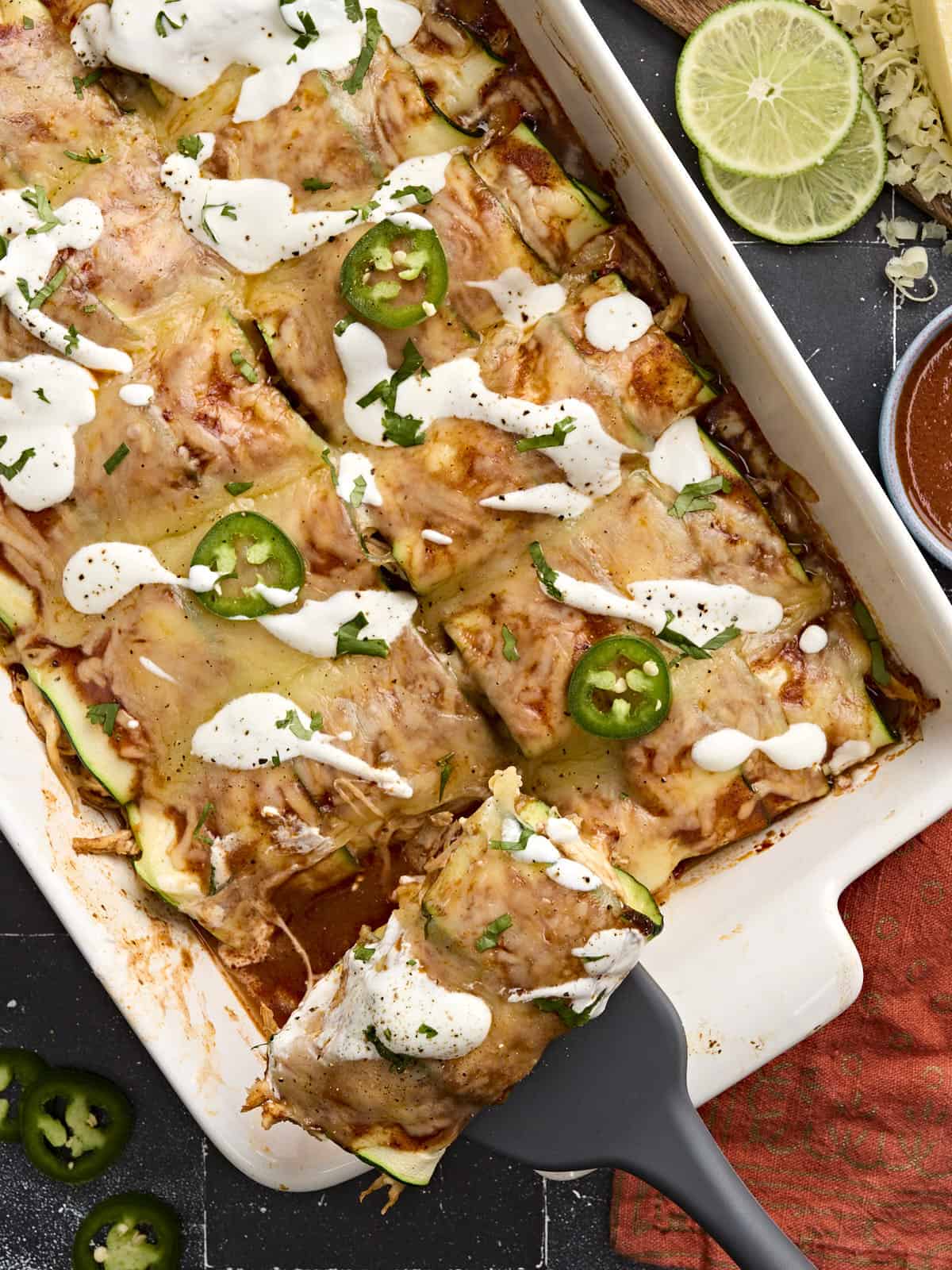 Overhead view of zucchini enchiladas topped with sour cream and sliced jalapenos.