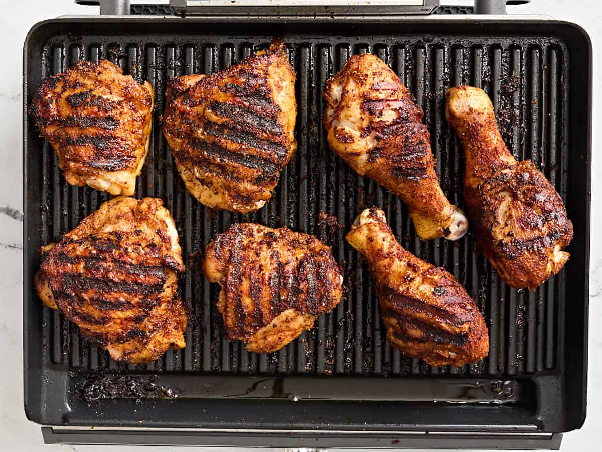 Dry rubbed grilled chicken thighs and drumsticks on a grill.