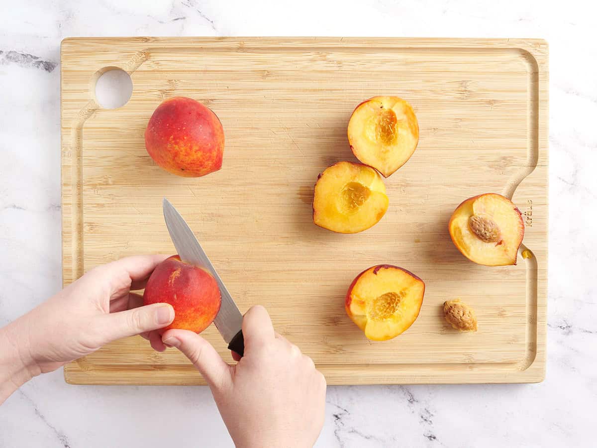 A knife slicing peaches in half.