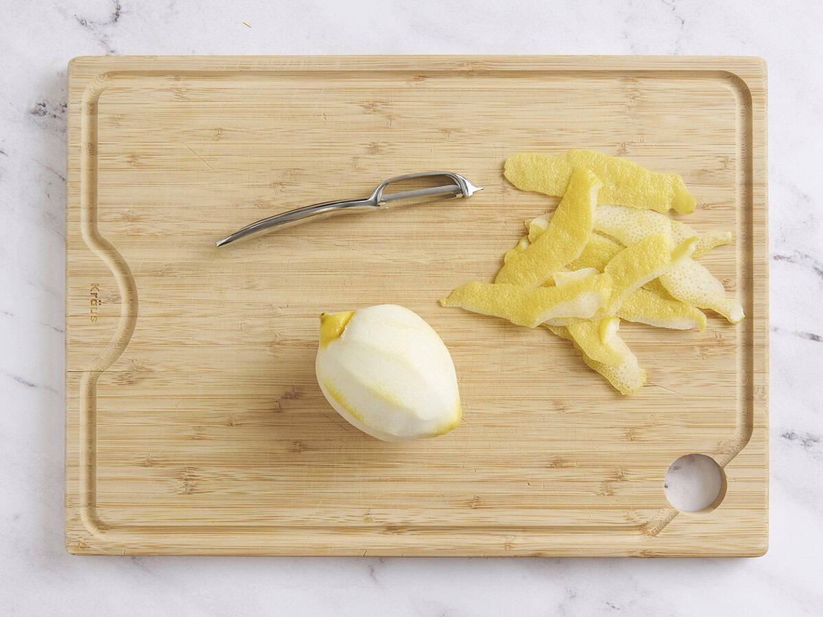 One peeled lemon on a wooden cutting board.