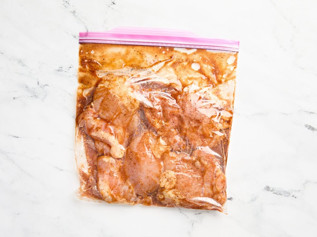 Chicken thighs marinating in a ziplock bag.