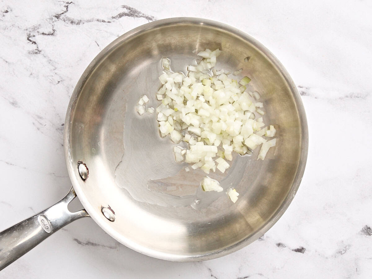 Minced onion sauteing in a skillet.