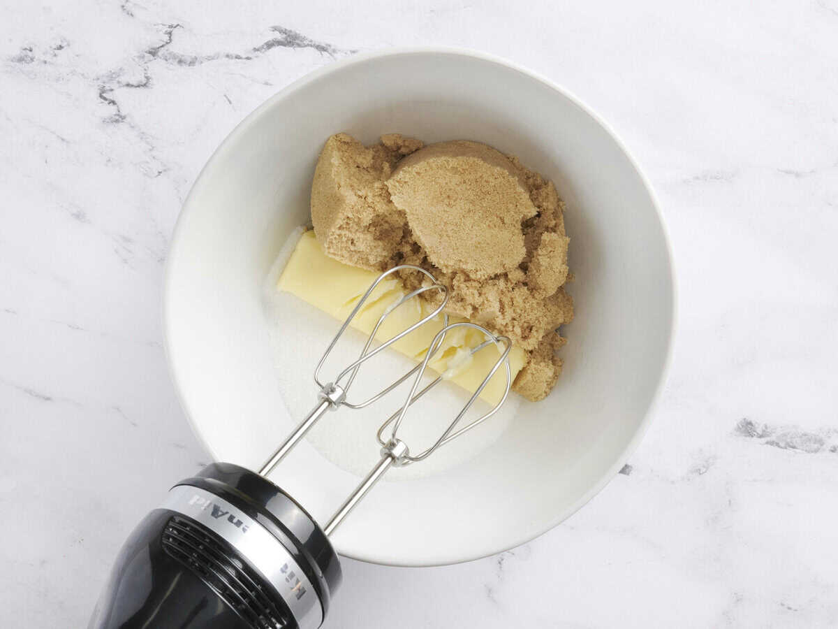 Sugar, brown sugar, and butter in a mixing bowl with a hand mixer.