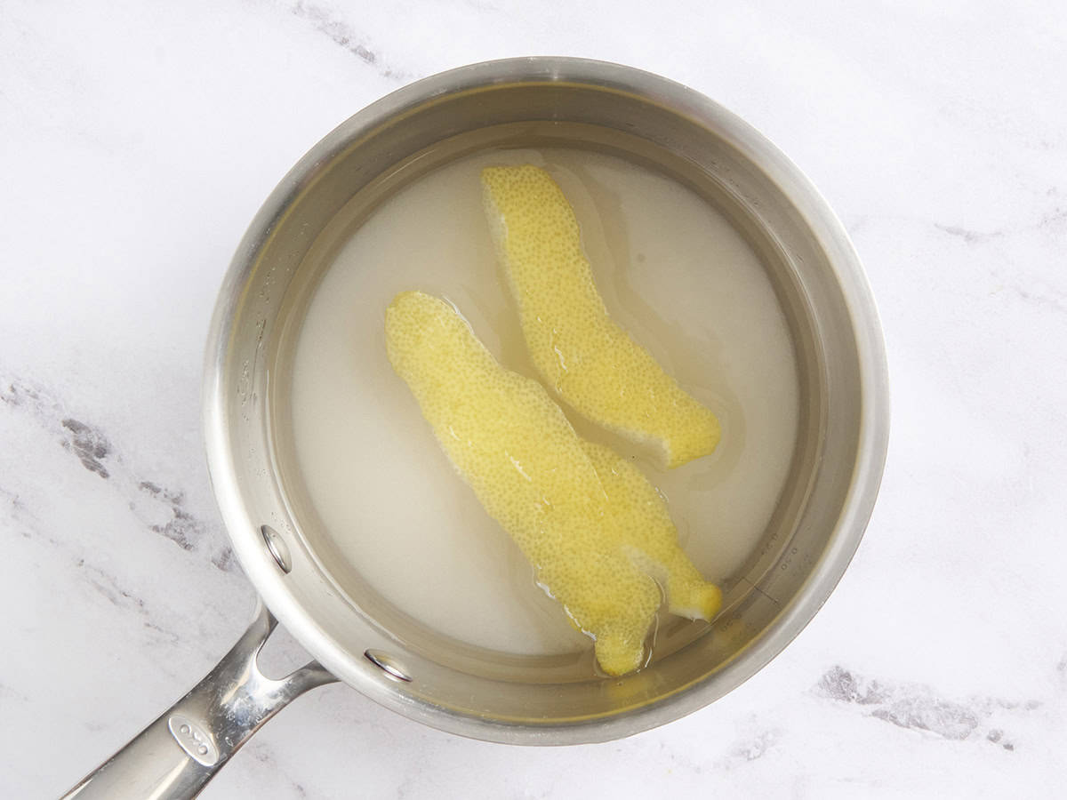 Lemon peels added to a saucepan of simple syrup.