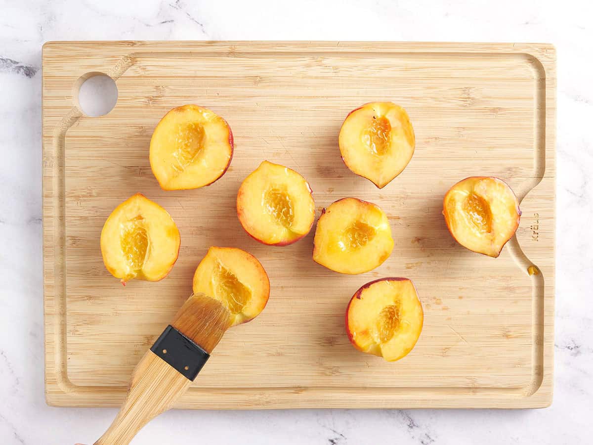 Peach halves being brushed with oil.