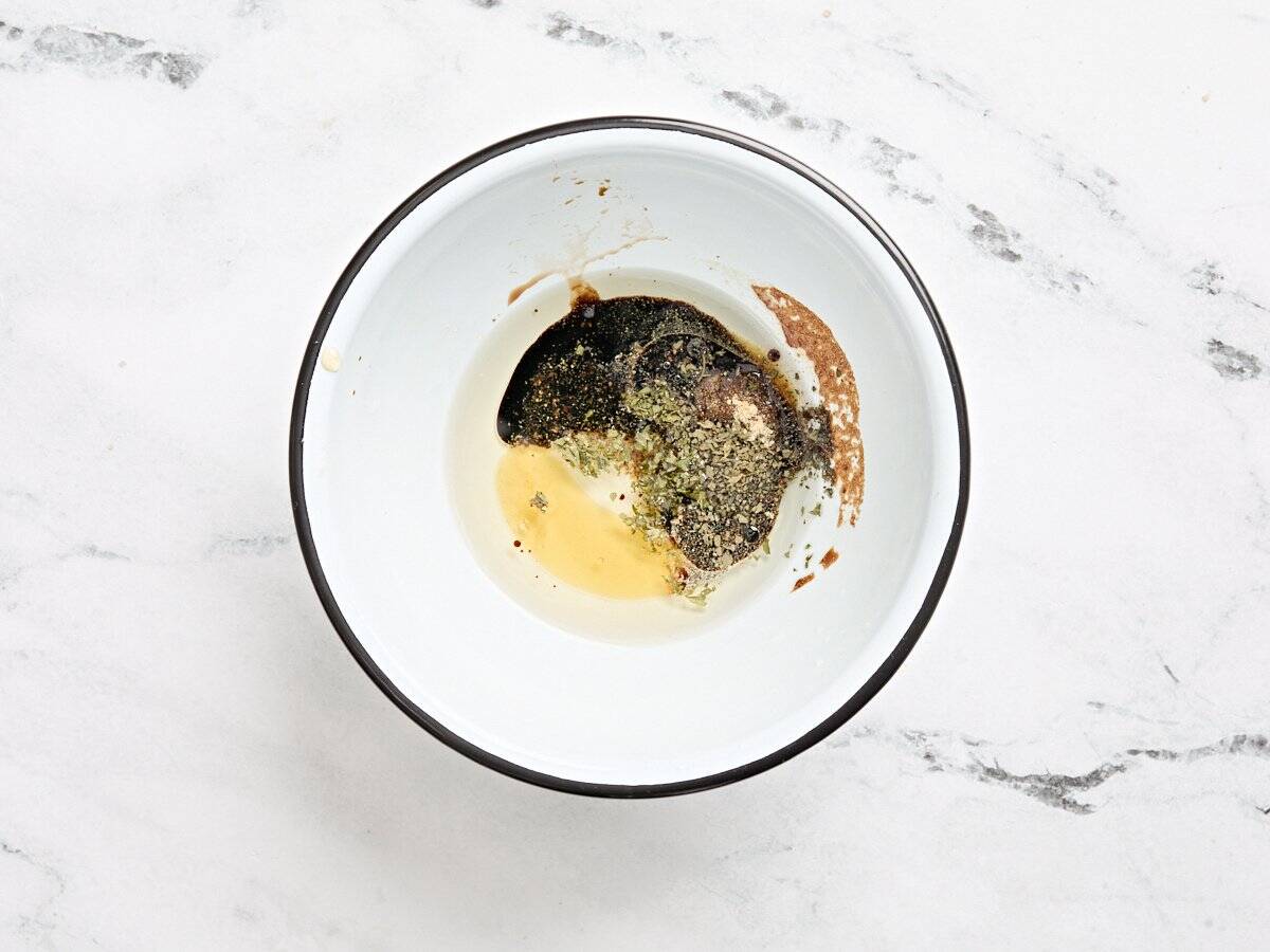 Oil, balsamic vinegar, honey and spices in a bowl.