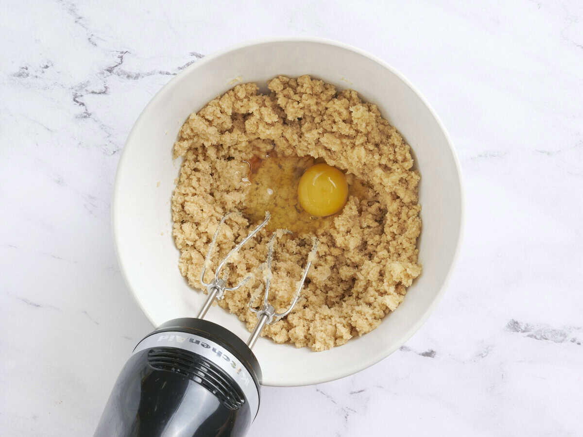 Add added to a bowl of creamed butter and sugar being mixed with a hand mixer.