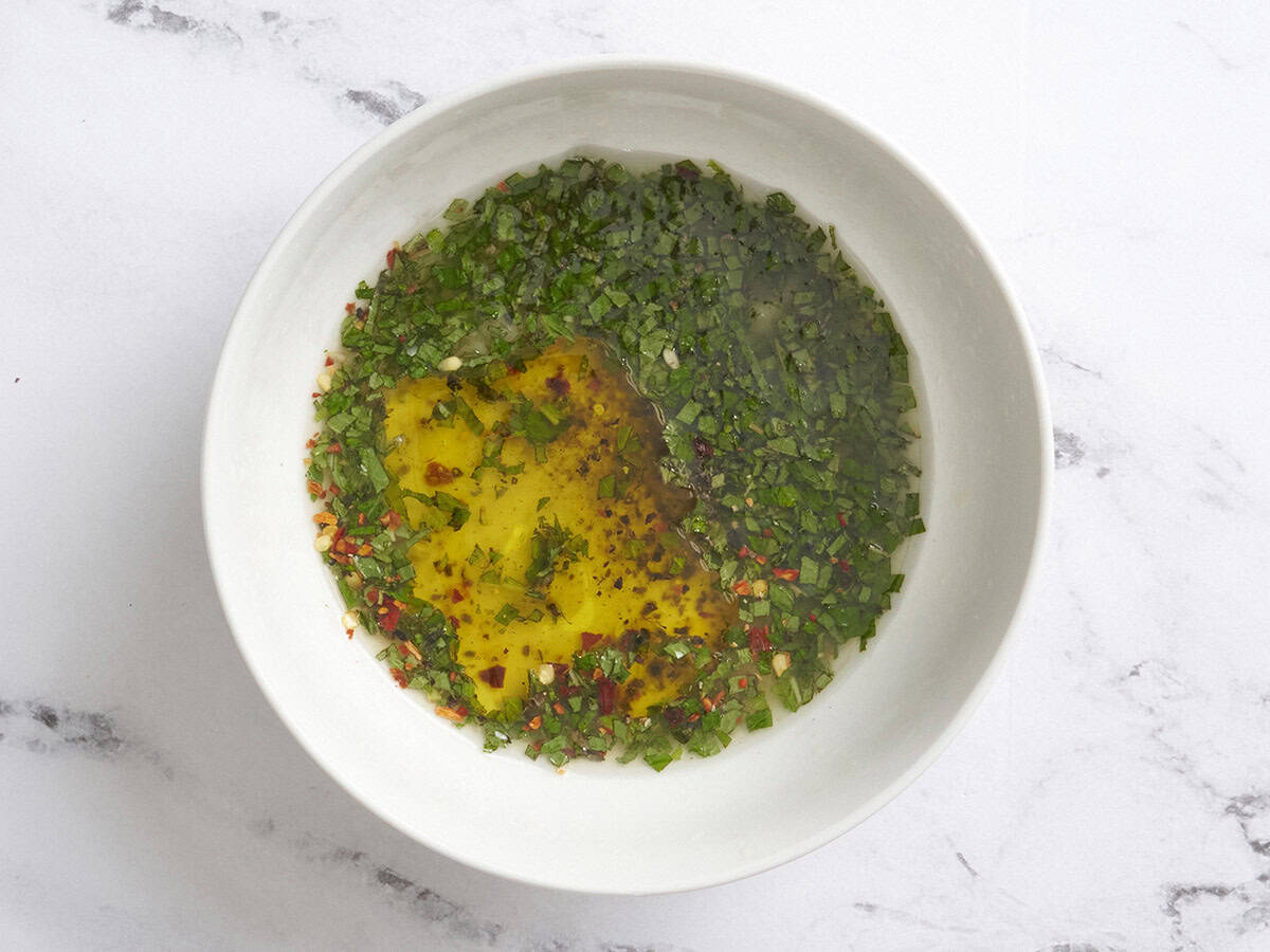The dressing for zucchini, corn and toasted almond salad in a bowl.