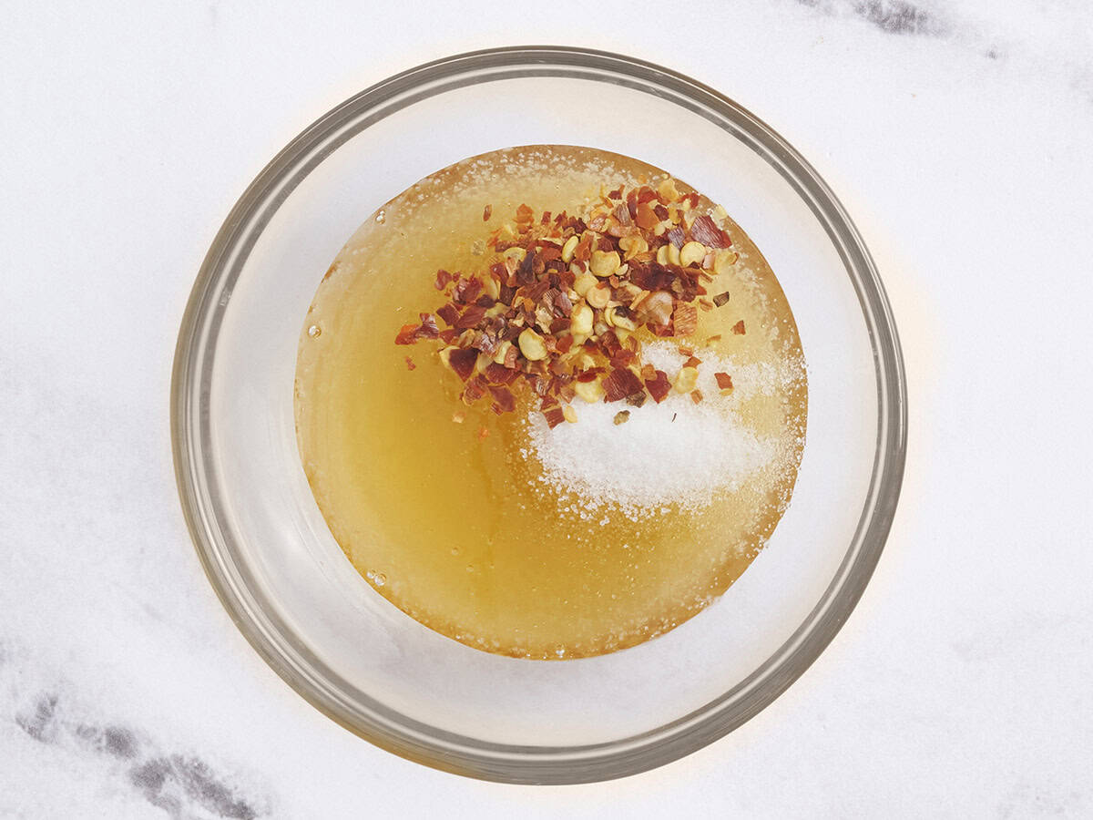 Salt and chili flakes added to a bowl of honey.