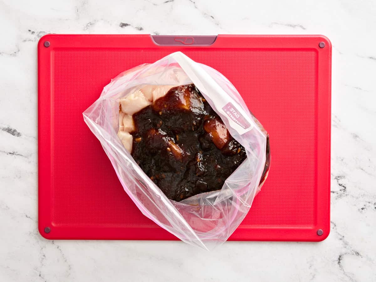 Teriyaki sauce being poured into a bag of diced chicken.