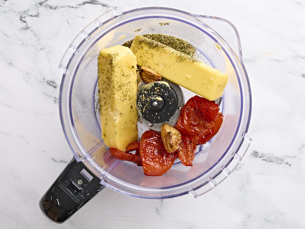 The ingredients to make tomato butter in a food processor.