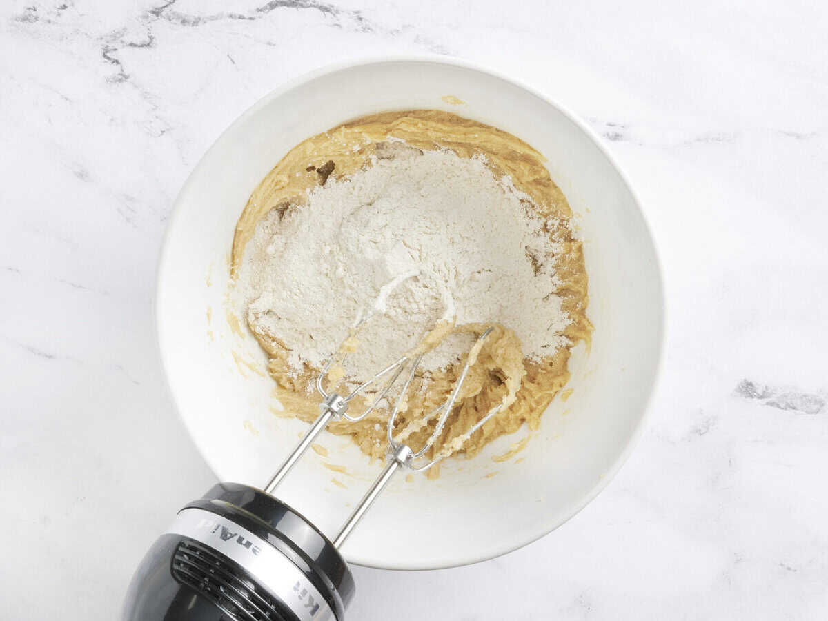 Flour added to the wet ingredients in a mixing bowl.