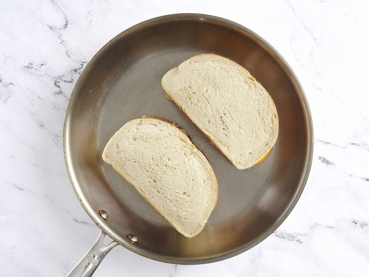 Two honey peach grilled cheese toasting in a frying pan.