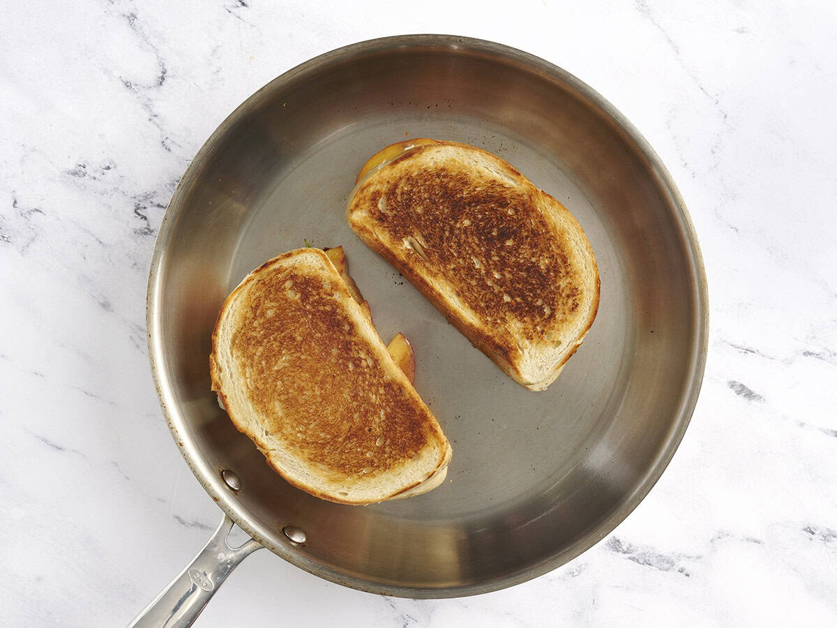 Two toasted honey peach grilled cheese in a frying pan.