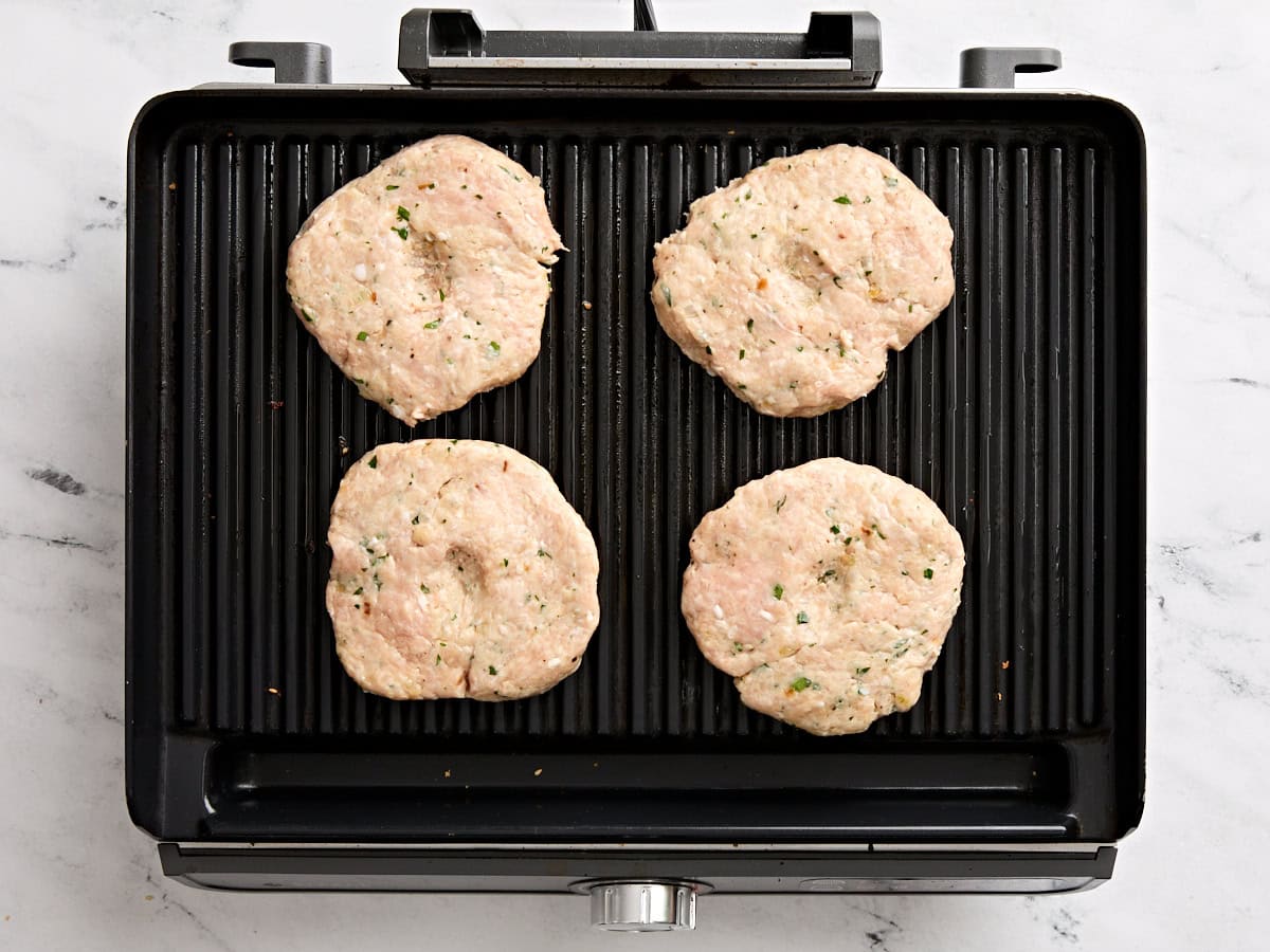 Chicken burger patties on a grill.