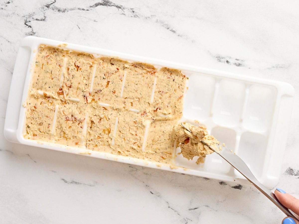Tomato butter being divided into an ice cube tray,