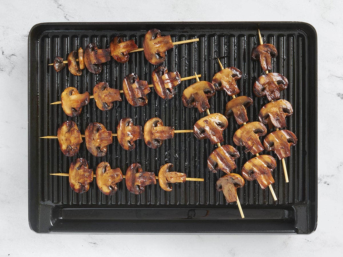 Finished smoky grilled mushroom skewers on a grill.