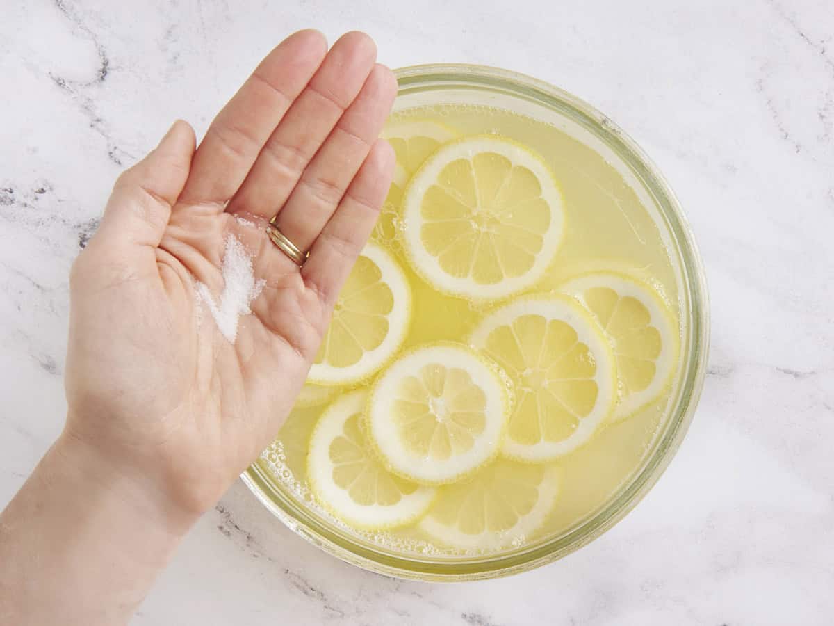 A pinch of salt being added to lemonade in a punch bowl.
