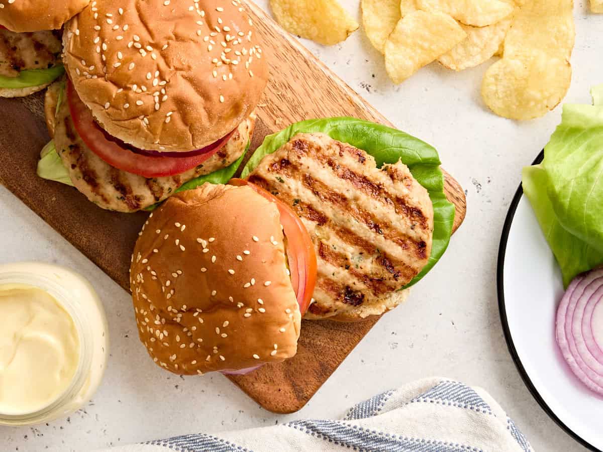Overhead view of a chicken burger on a wooden platter.