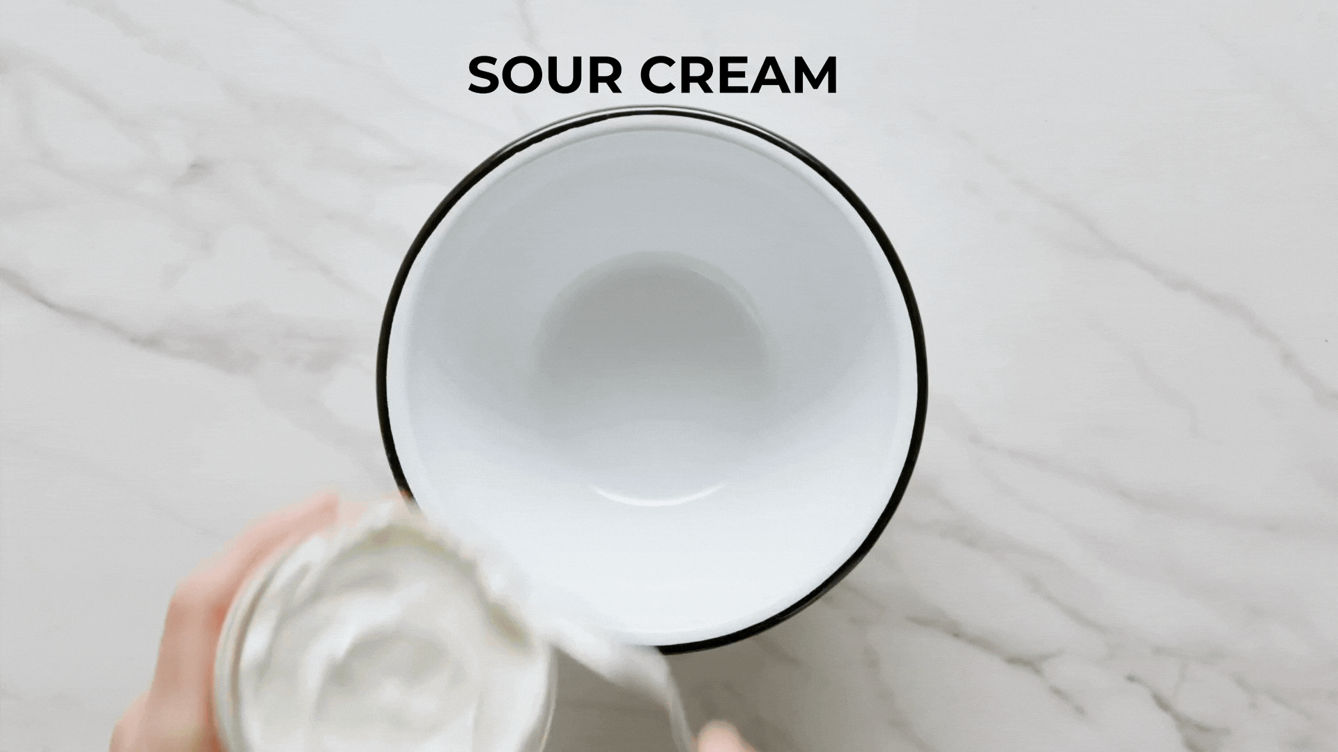 Sour cream and dill dressing in a bowl with a red spatula.