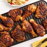 Dry rubbed grilled chicken drumsticks and thighs on a grill.