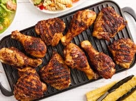 Dry rubbed grilled chicken drumsticks and thighs on a grill.