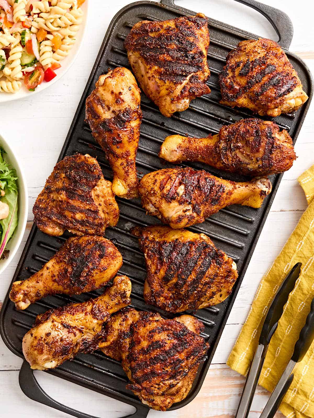 Dry rubbed grilled chicken drumsticks and thighs on a grill.