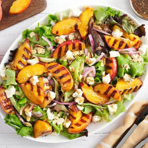 Overhead view of a grilled peach salad on a platter.