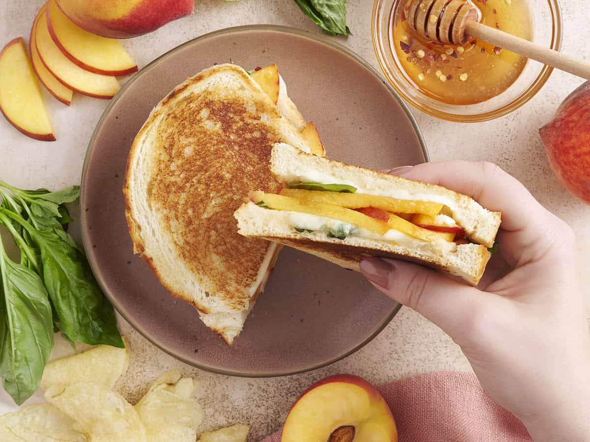 A hand holding a honey peach grilled cheese sandwich.