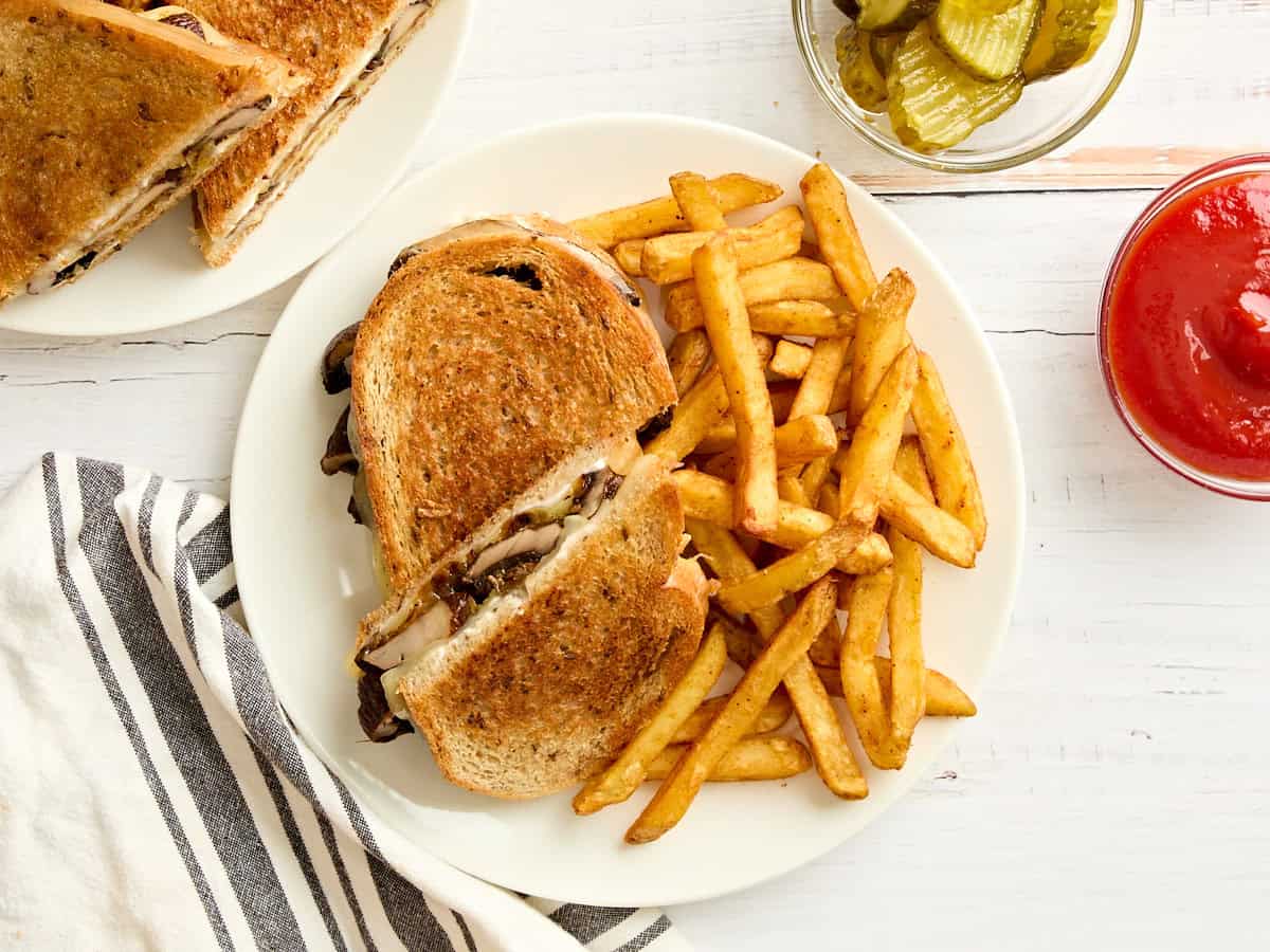 Overhead view of a mushroom patty melt and fries on a plate.