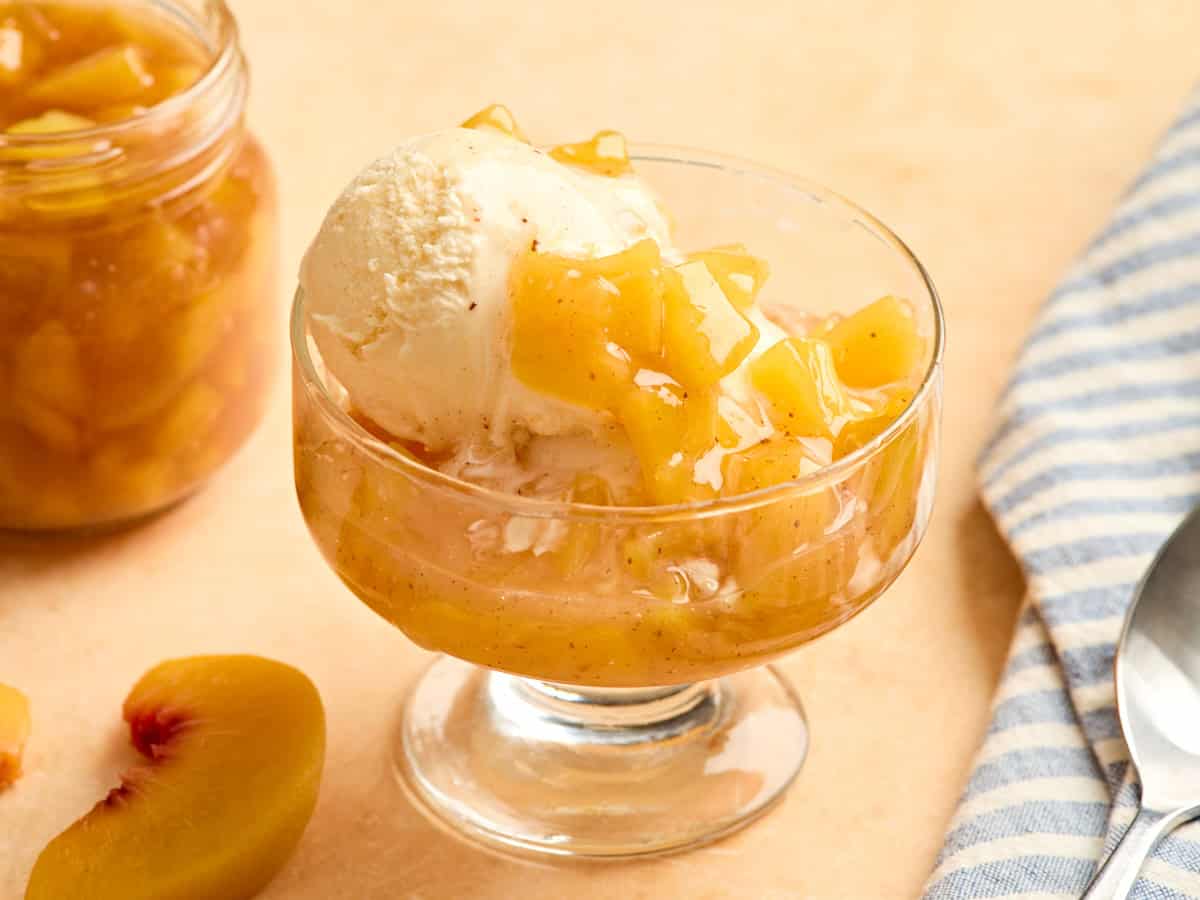 Vanilla ice cream and peach sauce in a glass bowl.
