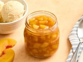 Side view of homemade peach sauce in a glass jar.