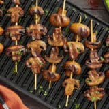 Overhead view of smoky grilled mushroom kebabs on a grill.