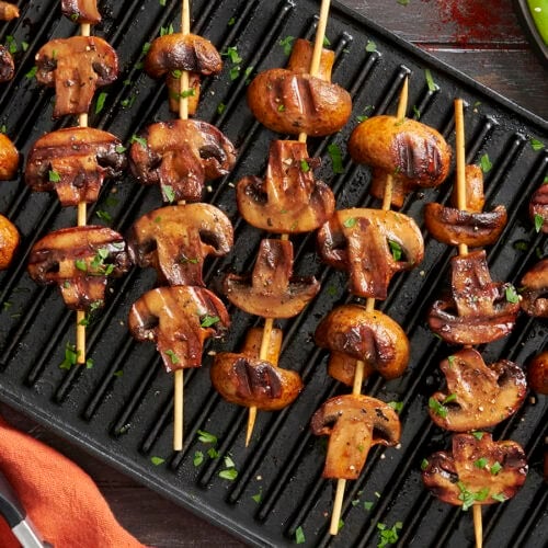 Overhead view of smoky grilled mushroom kebabs on a grill.