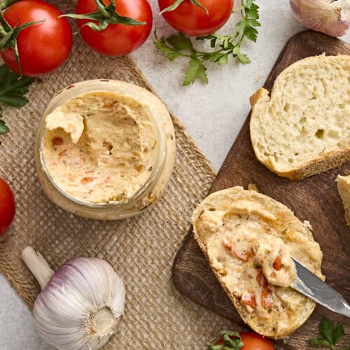 Overhead view of a jar of tomato butter, with some spread on a slice of bread.