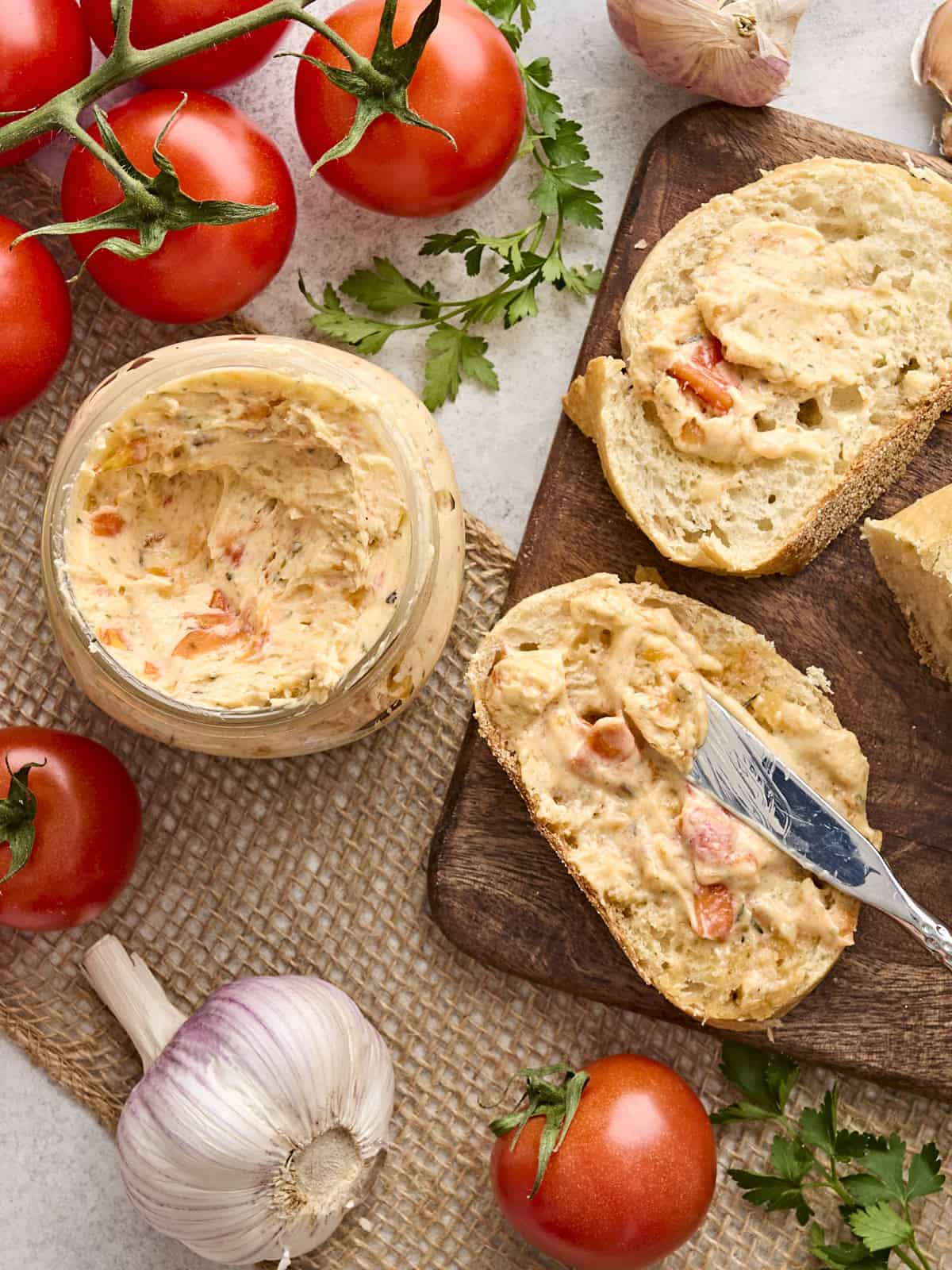 Overhead view of a jar of tomato butter, with some spread on a slice of bread.