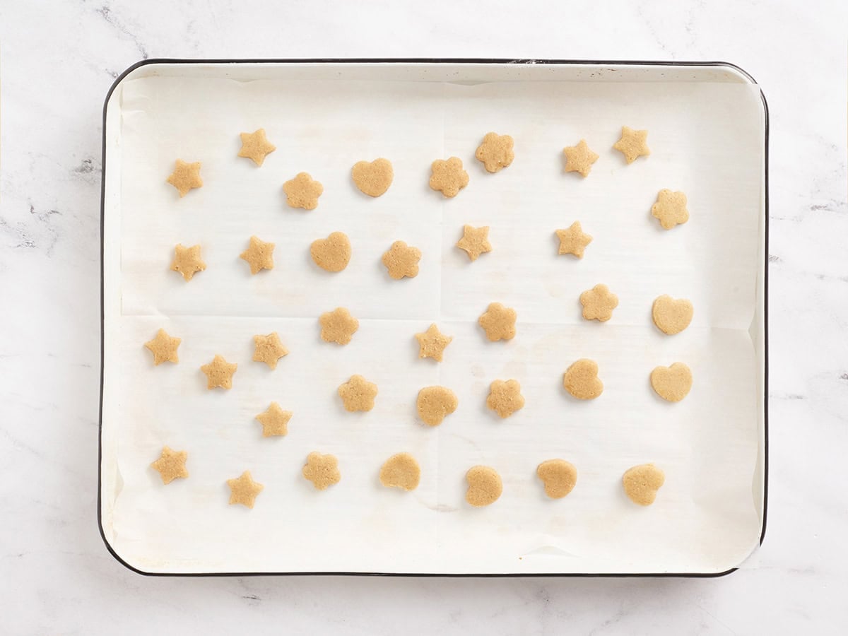 Mini cookies cut out on a baking sheet.