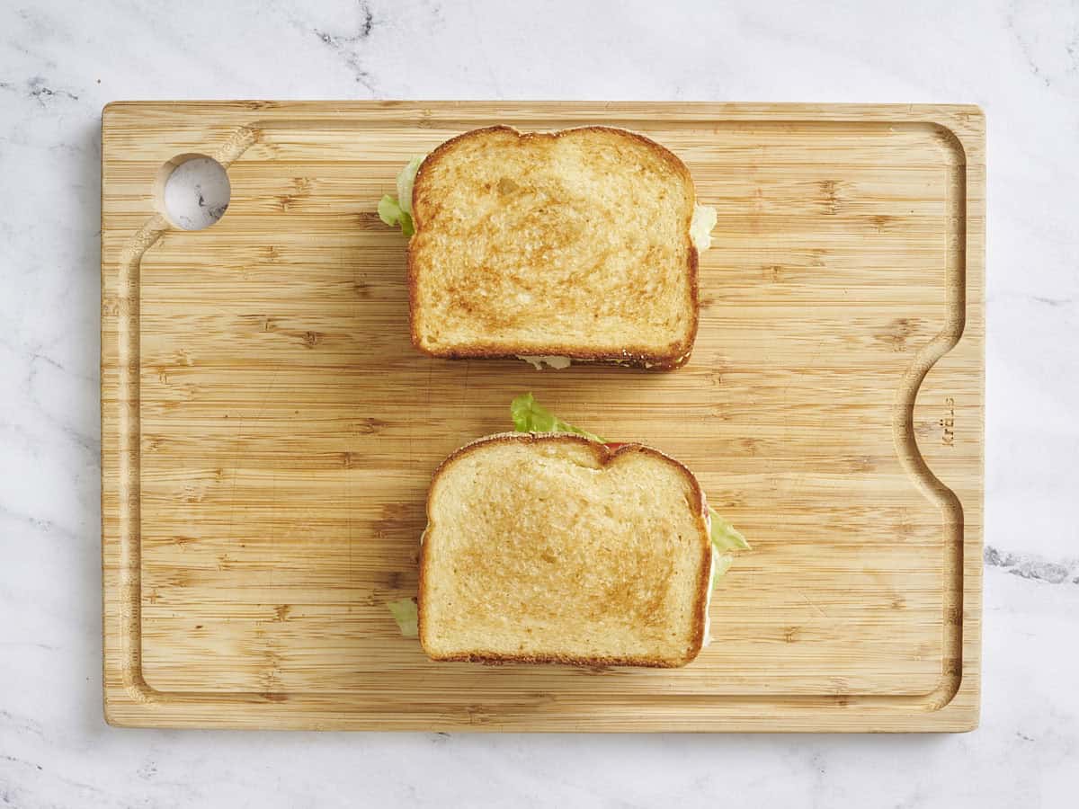 Overhead view of two classic BLT sandwiches on a wooden cutting board.