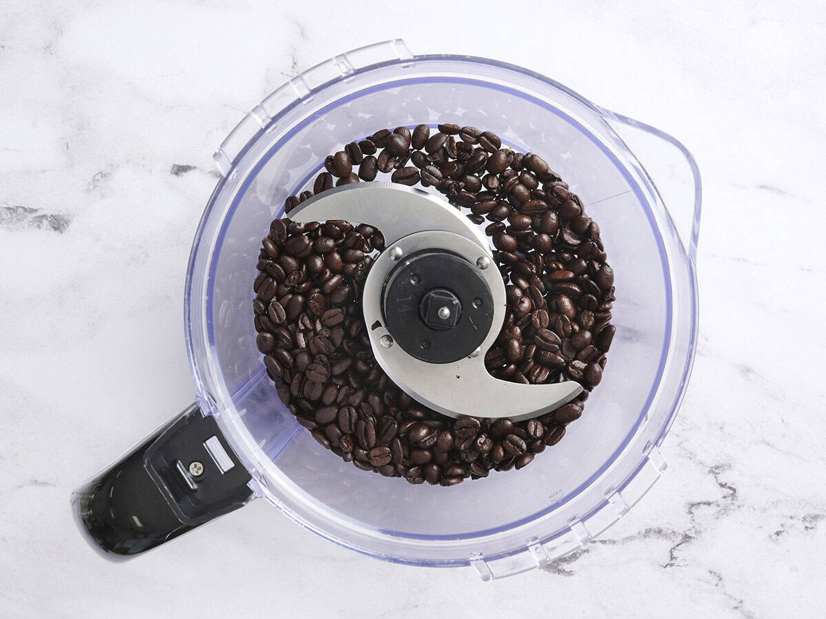 Coffee beans added to a food processor.