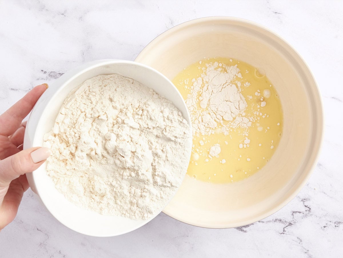 Flour being poured into an egg and milk mixture.