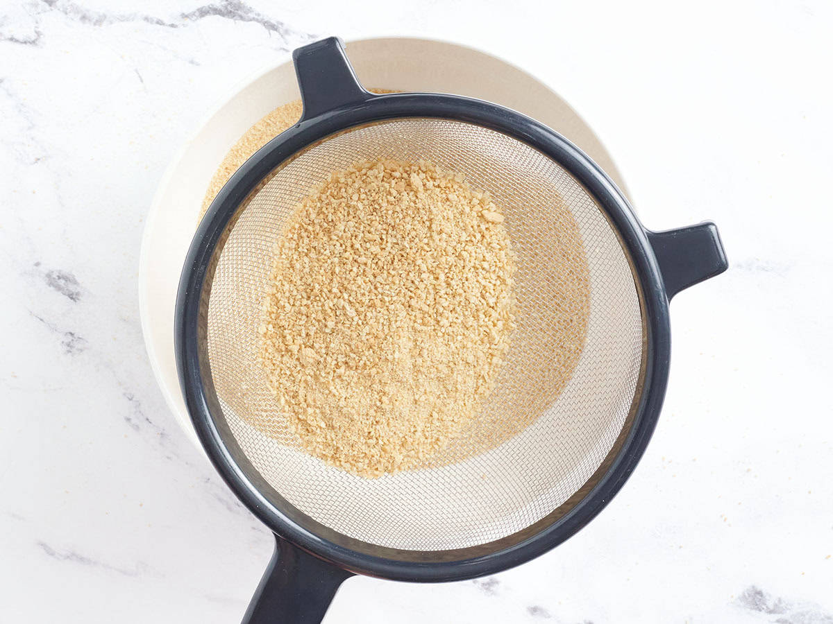 Crushed graham crackers being sifted.