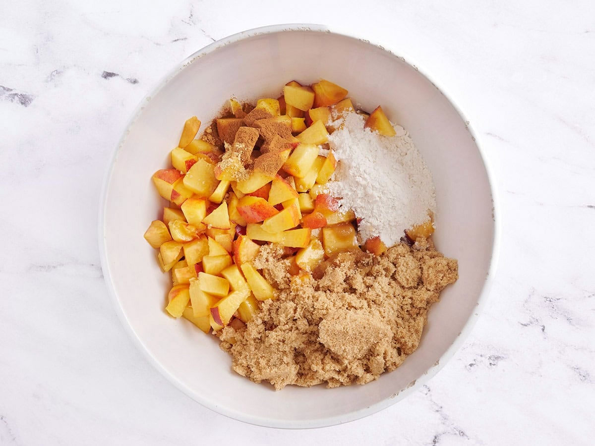 Diced peaches and sugar in a bowl.