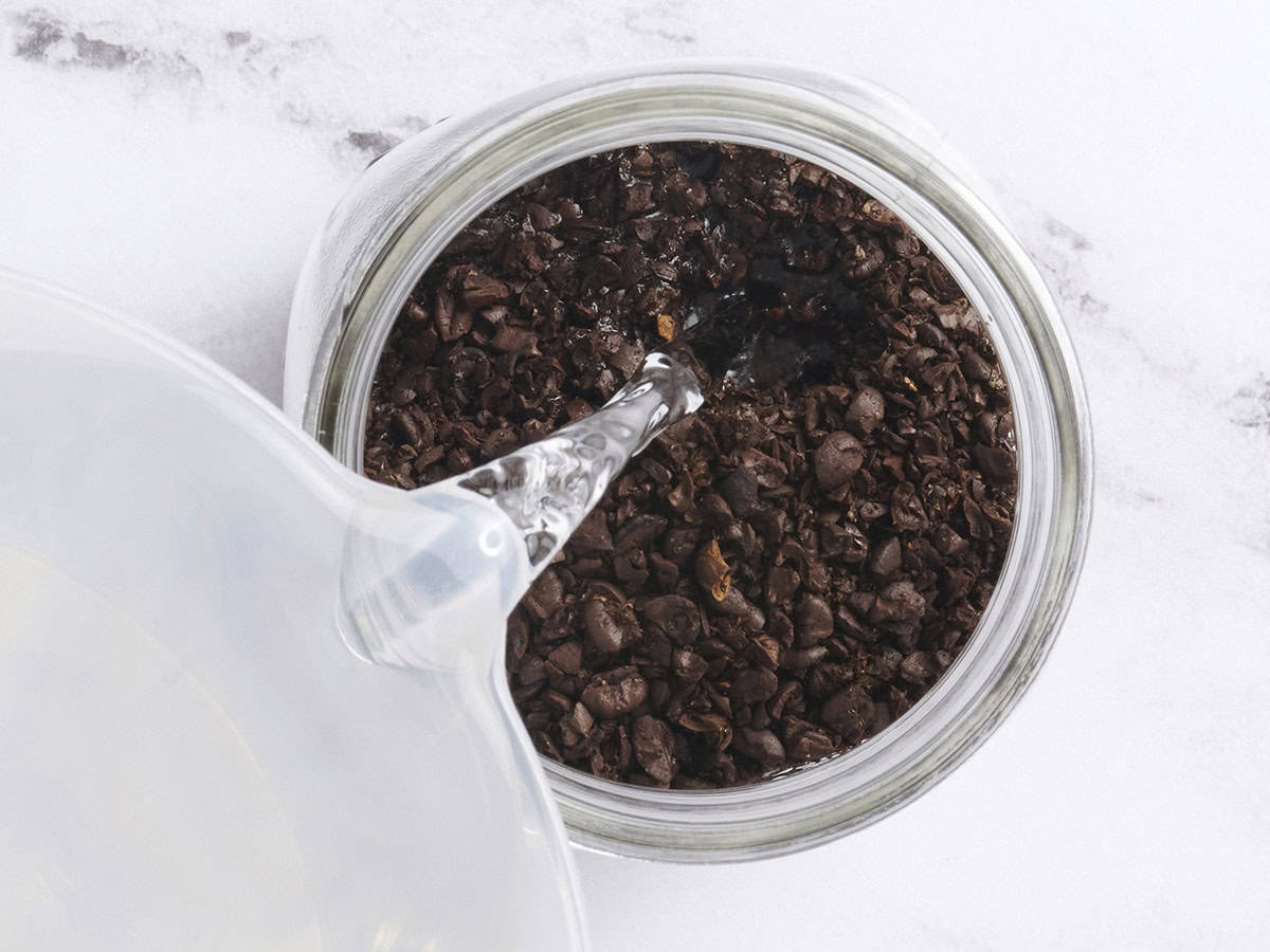 Cold water being poured into ground coffee beans.