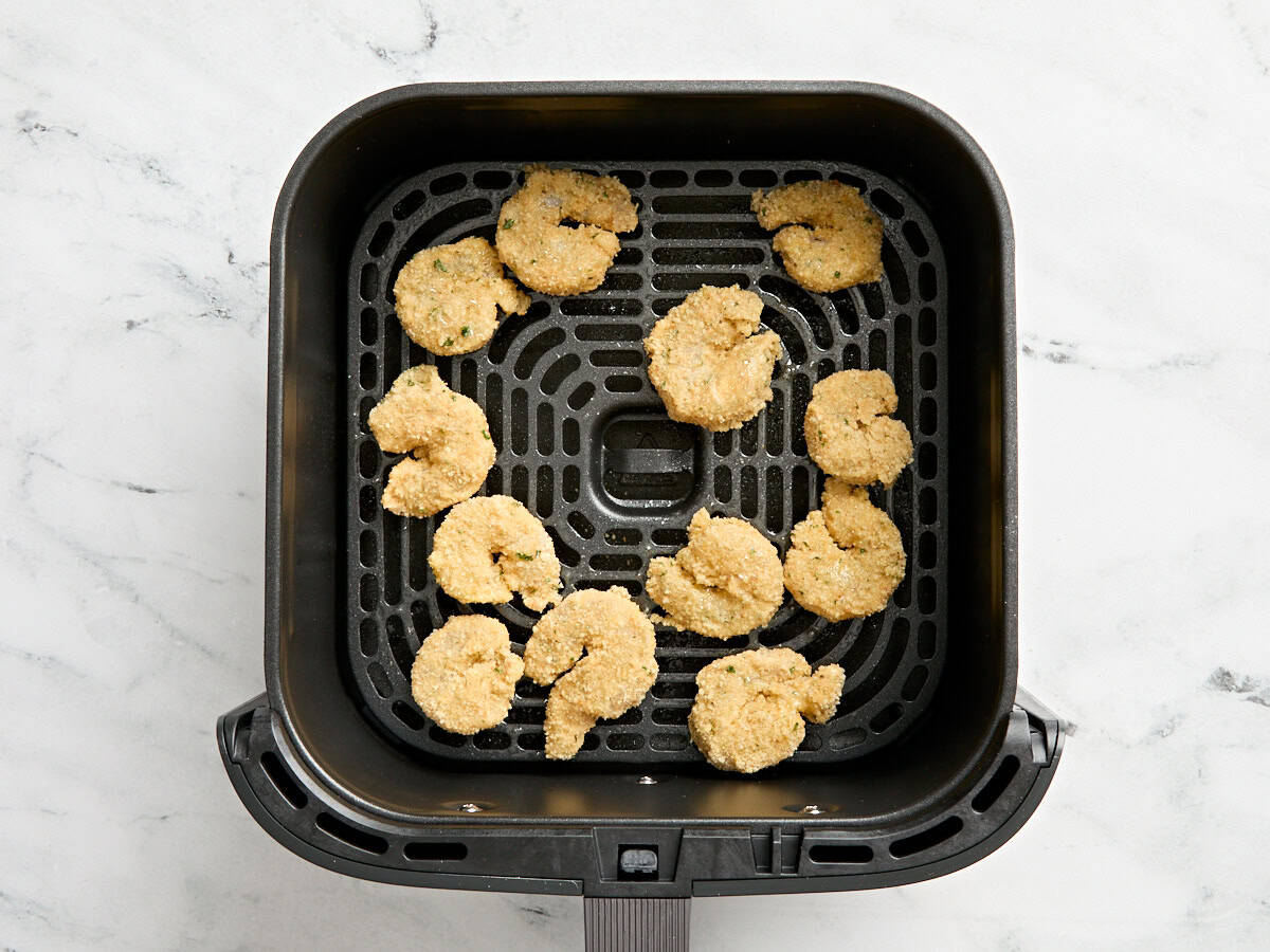 Breaded shrimp in an air frier basket.