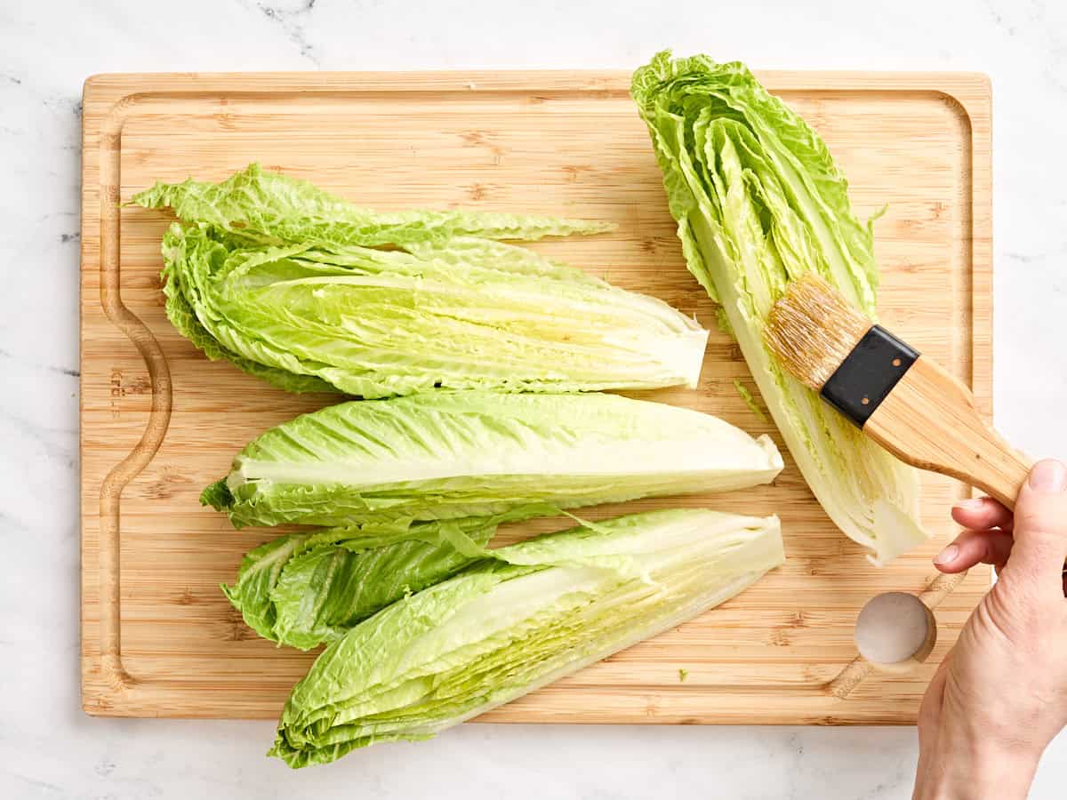Romaine hearts being brushed with oil.