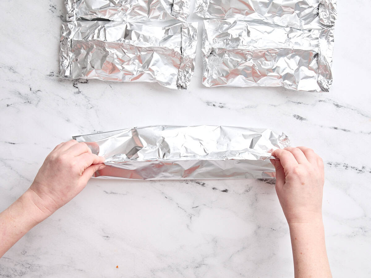 Hands folding a shrimp foil packet.