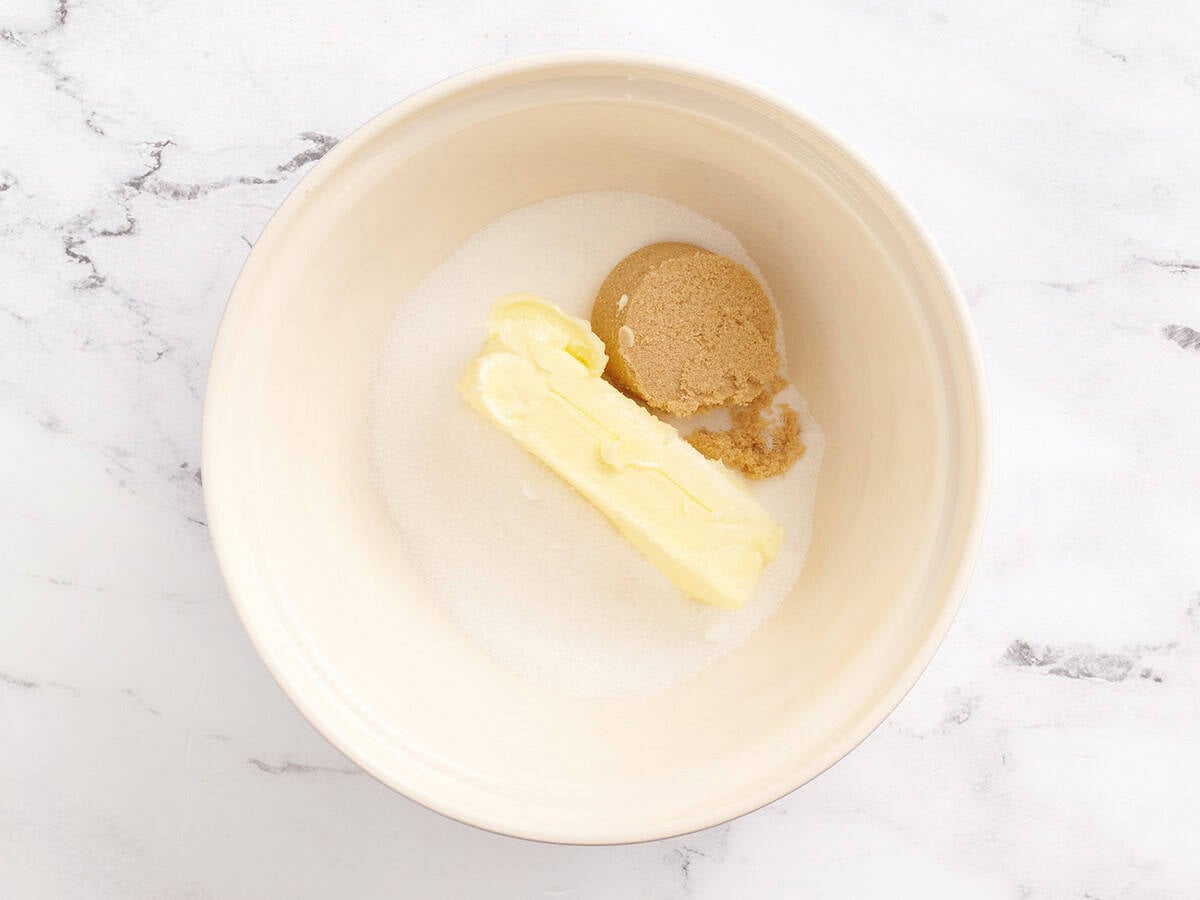 Granulated sugar, brown sugar, and butter added to a mixing bowl.