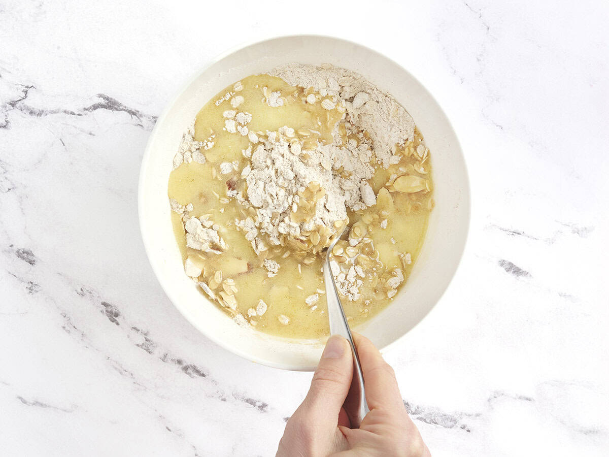Melted butter being mixed into a crumble topping in a bowl.